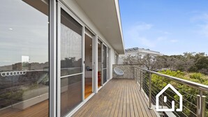 A modern house with a wooden deck and large sliding glass doors leading to an interior space. - Banksia Beach Retreat *1 NIGHT FREE* (Blairgowrie)