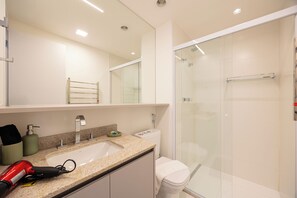 Features a sleek vanity, granite countertop, large mirror, and glass-enclosed shower area.