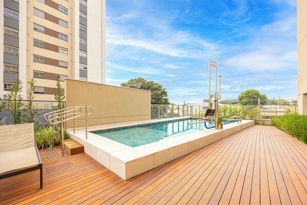 Relax by the rectangular pool surrounded by a low concrete edge and lounge chairs.