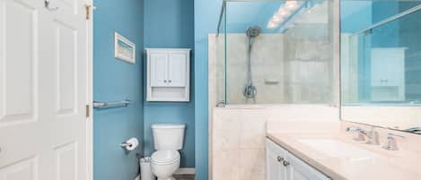 A bathroom with a toilet, sink, and shower.