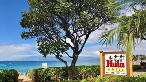 Schild für 'Hula Grill' mit Blick auf das Meer und einem Baum im Vordergrund.