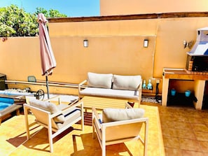 Un patio con piscina, una parrilla y un conjunto de sofás.