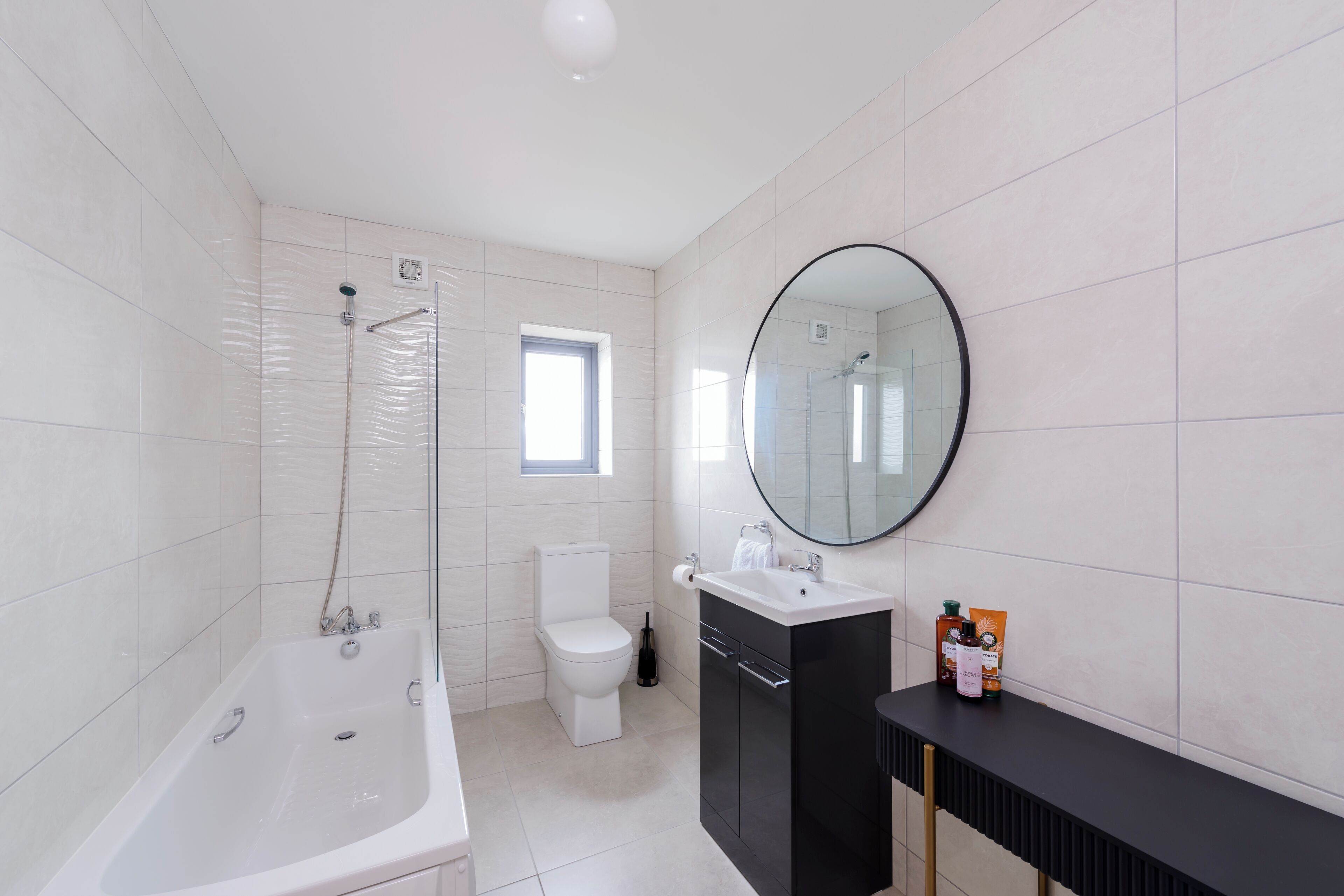 Une salle de bain moderne avec une baignoire, des toilettes, un lavabo et un grand miroir.