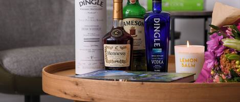 A wooden tray with bottles of whiskey, a candle, and a menu.