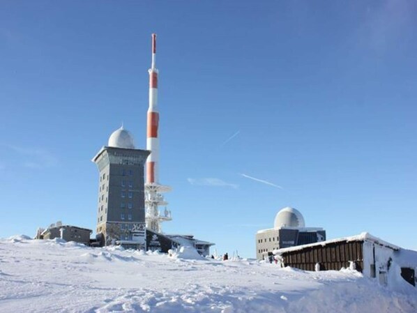 A snow-covered landscape with a tall tower and a building with a dome. - Ferienhaus in Schierke for 6 Personen (Wernigerode)