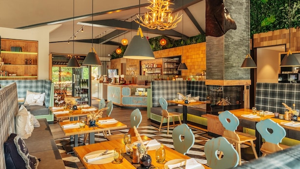 A restaurant with wooden furniture, a bar area, and a green wall. - Ferienhaus in Schierke for 6 Personen (Wernigerode)