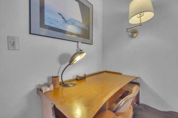 A wooden desk with a desk lamp, a framed picture of a seascape, and a wall-mounted lamp. - 2 Blocks to Beach | Firepit | Sandbox | BBQ | Work (Carlsbad)