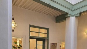 A spacious interior with a wooden dining table, a patterned rug, and a view of a balcony with decorative lighting. - La Maison des Amis  (Fes)