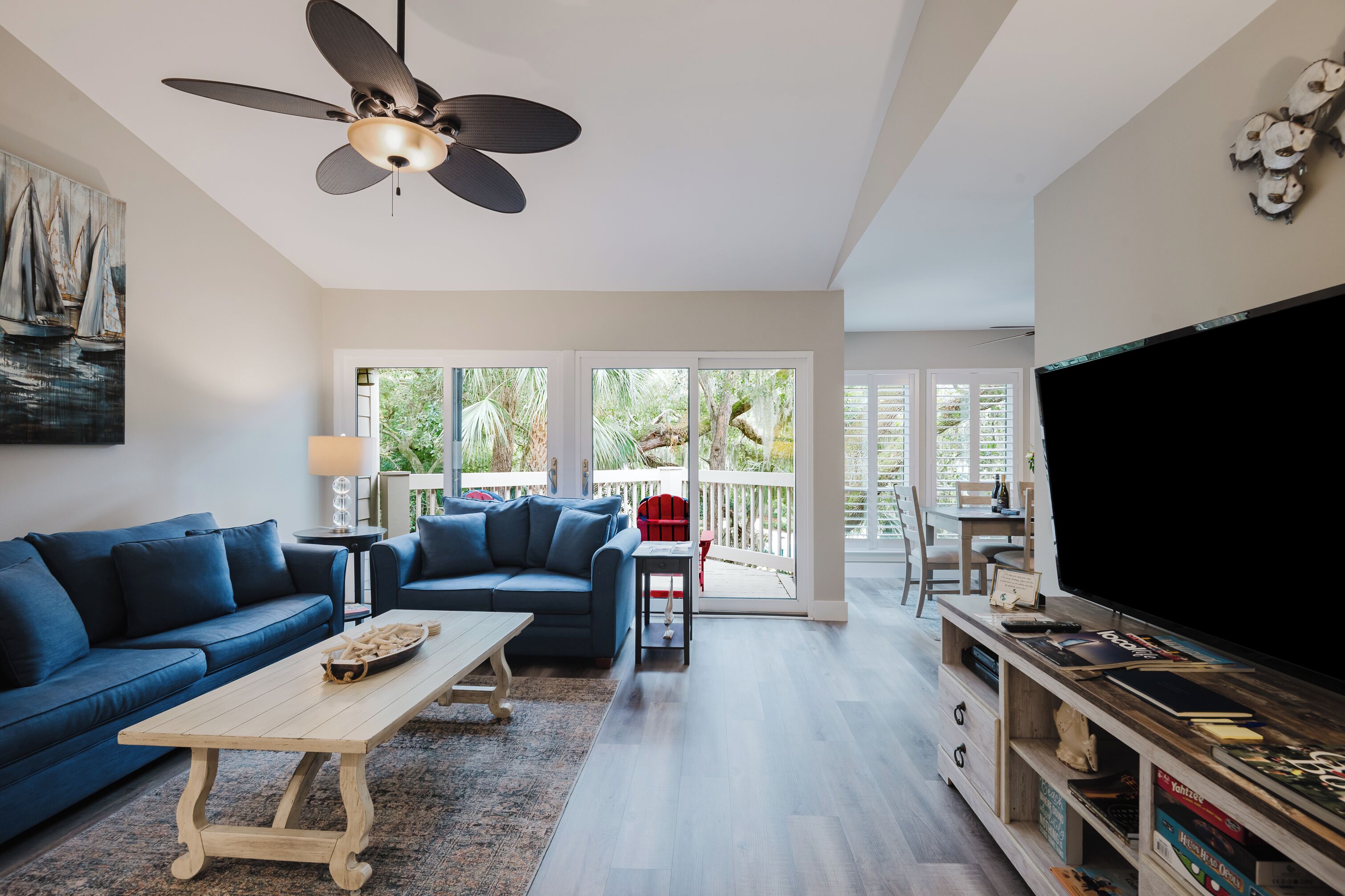 Un salon moderne avec un canapé bleu, une table basse en bois et un téléviseur à écran plat posé sur un meuble en bois.