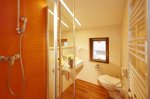 Une salle de bain avec une douche à parois de verre, un lavabo blanc et des toilettes.