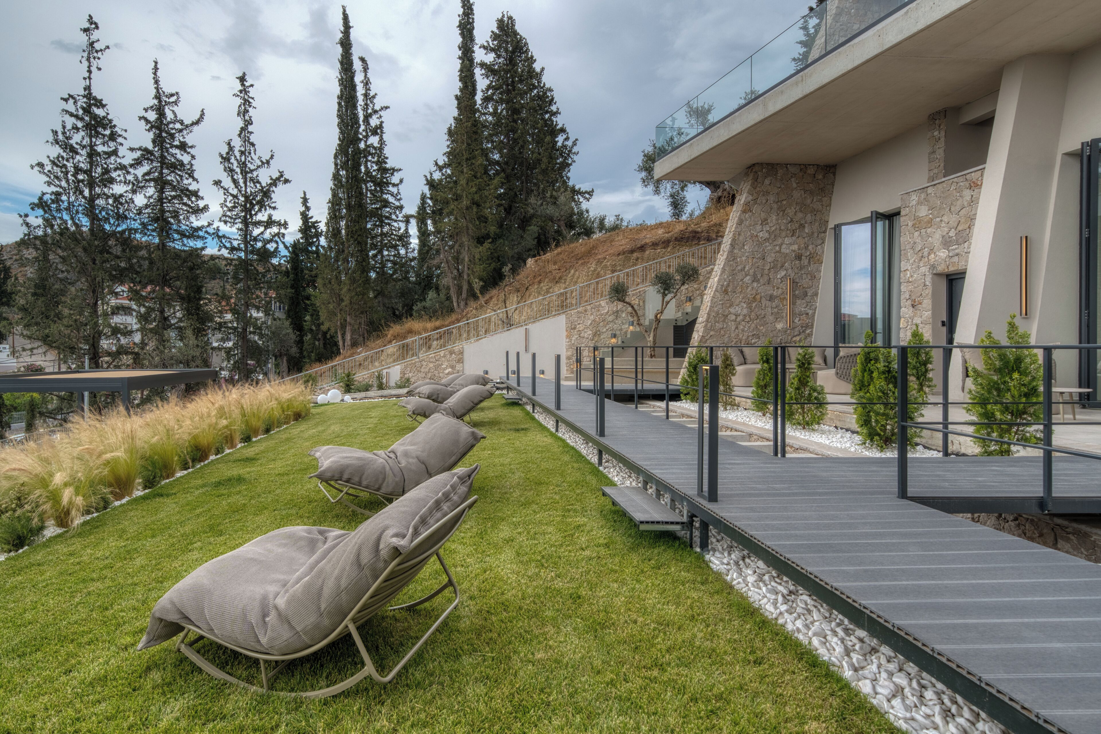 A modern outdoor seating area with lounge chairs and a wooden deck.