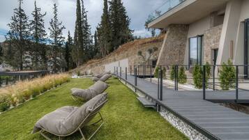 A modern outdoor seating area with lounge chairs and a wooden deck.