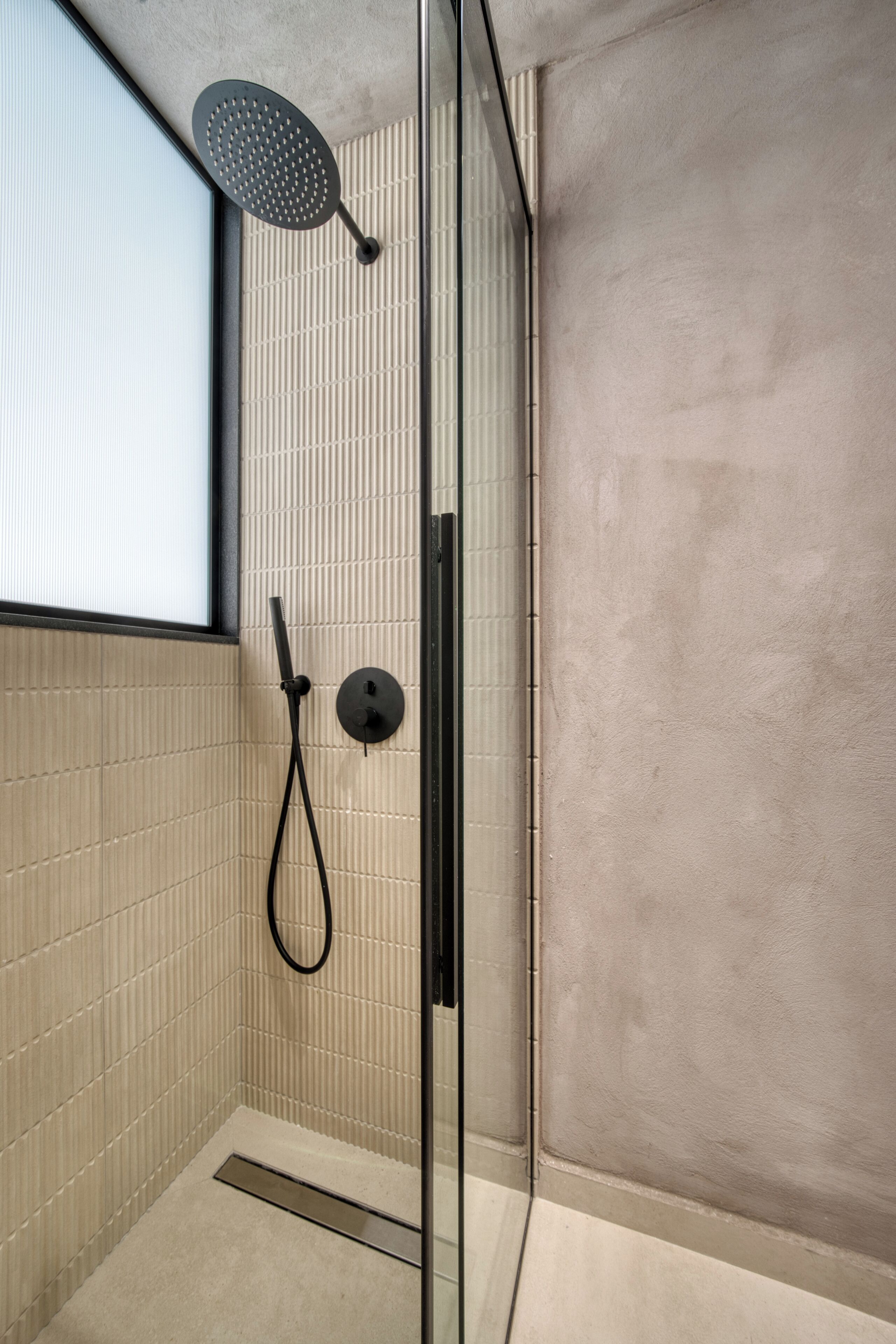 A modern shower with a handheld showerhead and a wall-mounted control panel.