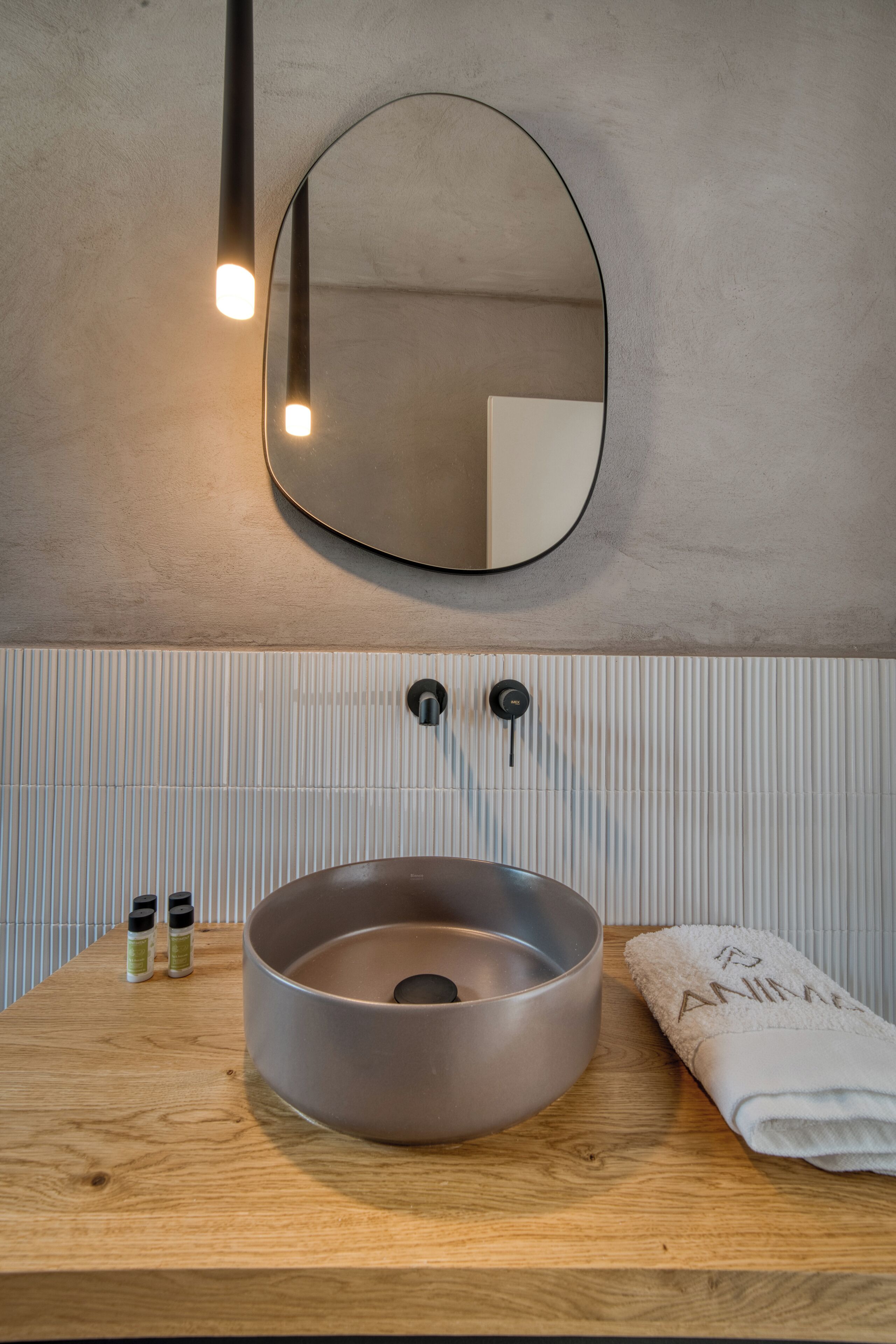 A bathroom with a round sink, a mirror, and a towel.