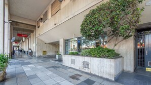 Un vaste couloir intérieur doté d’un sol carrelé, d’un grand bac à plantes et d’une entrée en verre.