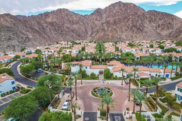 A residential area with houses, palm trees, and a mountain backdrop.