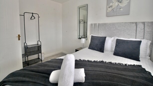 Quarto de hotel com uma cama, uma cadeira suspensa, um espelho e um quadro na parede.