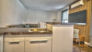 Une cuisine moderne dotée d’un évier encastré, d’un plan de travail en bois et d’un climatiseur fixé au mur.
