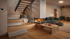A modern living room with a wooden staircase, a fireplace, a sofa, and a coffee table. - Villa Immortella, GreenTree - 6 persons, 3 bedroom luxury villa with seaview (Rabac)