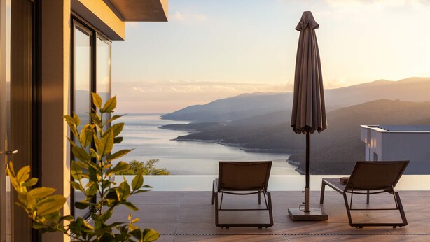 A terrace with two lounge chairs and an umbrella, overlooking a body of water and distant hills. - Villa Immortella, GreenTree - 6 persons, 3 bedroom luxury villa with seaview (Rabac)