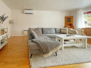 Un salon moderne avec un canapé d’angle, une table basse et un lampadaire.