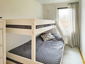 Una cama litera con escritorio y ventana con cortinas.