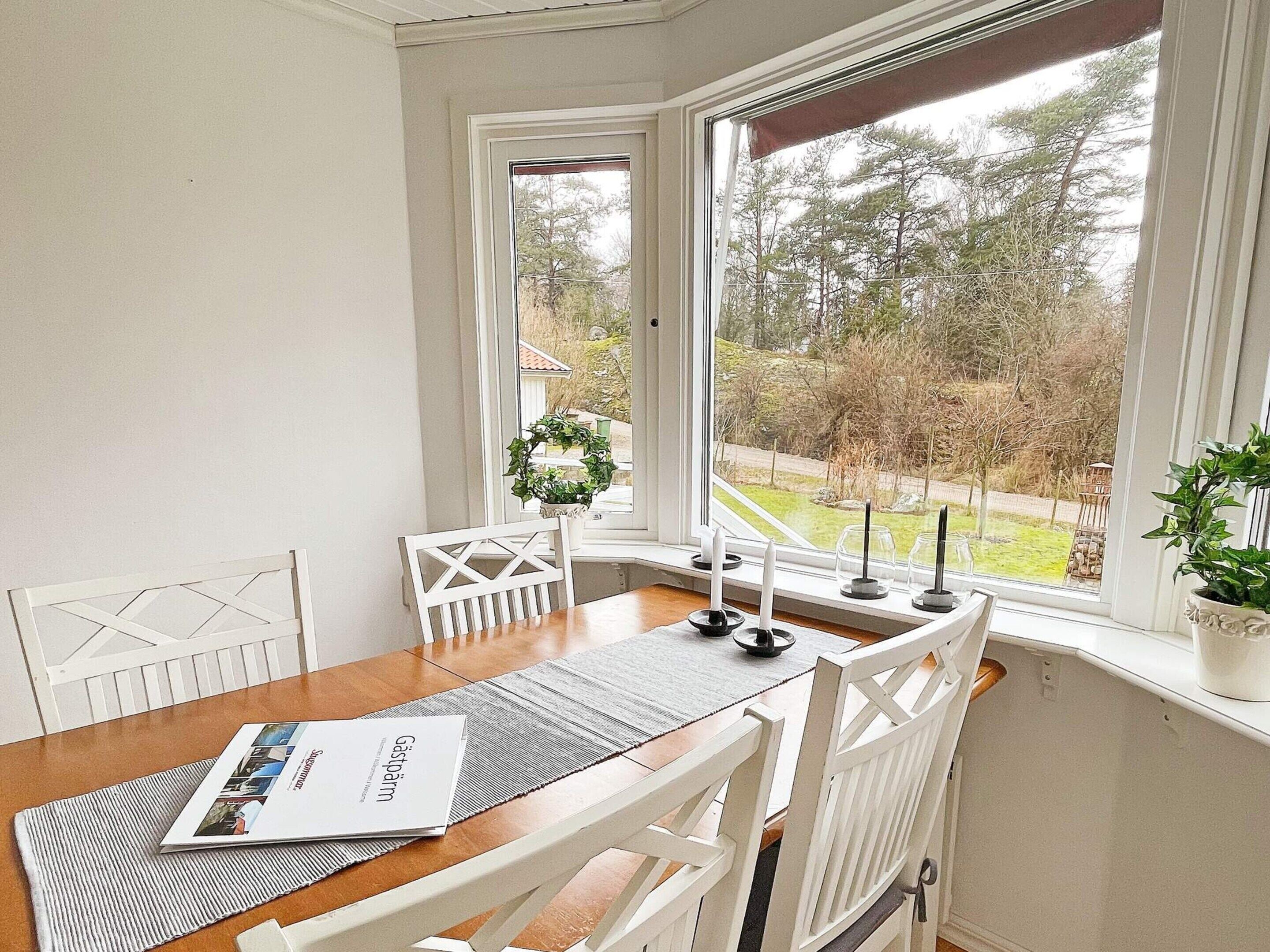 A dining area with a wooden table, white chairs, a placemat, and a menu.