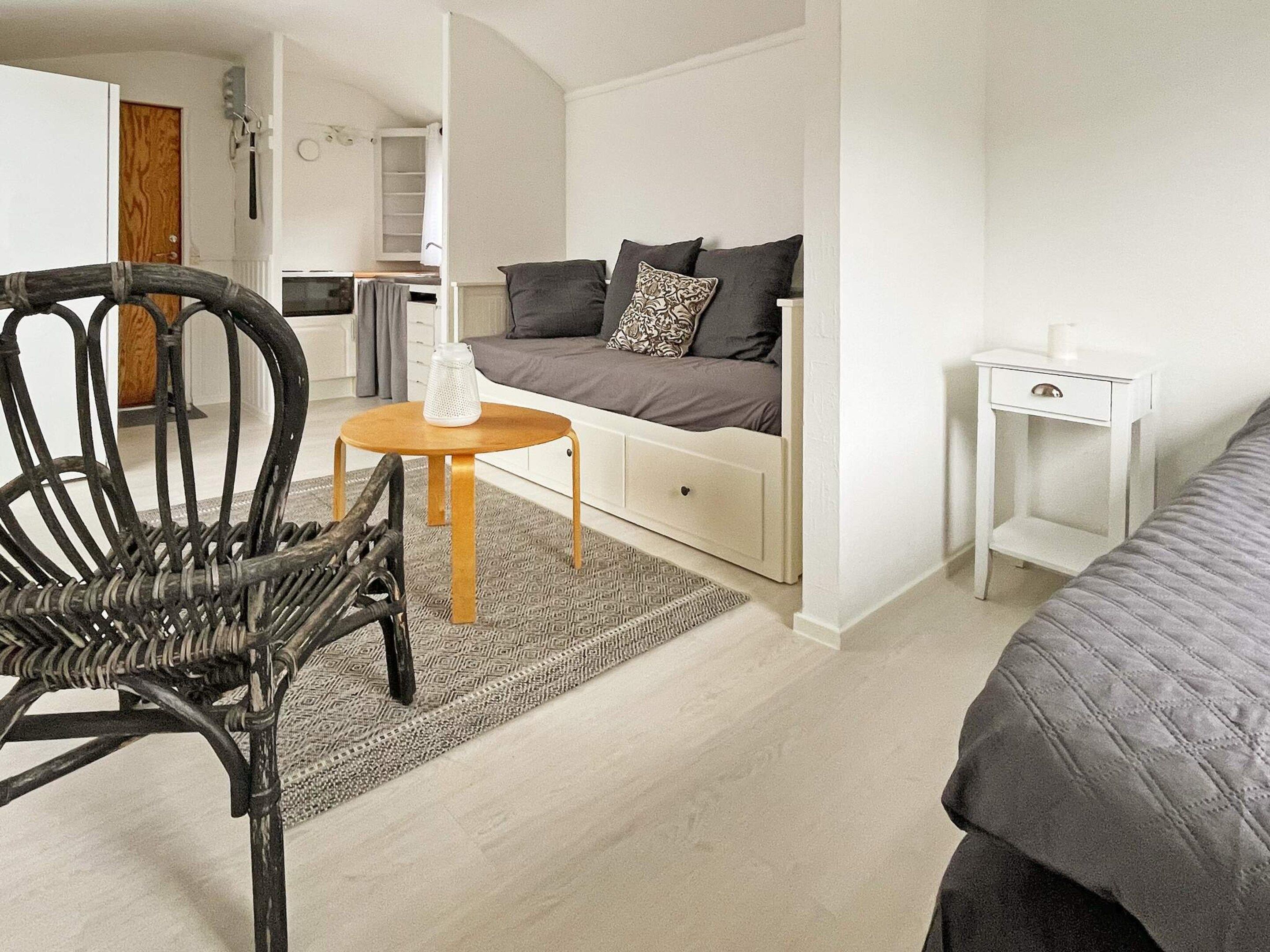 Une chambre à coucher de taille réduite, comprenant un lit simple, une petite table de chevet, une chaise et un canapé-lit.