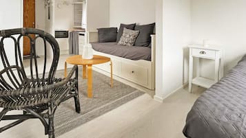 A compact living space with a sofa, a small table, a chair, and a bedside table.