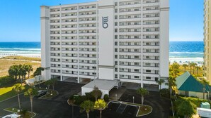 A high-rise hotel with a prominent '6' logo, multiple balconies, and a view of the beach. - 30-Foot Oceanfront Balcony |Oceanfront Pool|Heart of Destin (Destin)