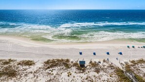 A beach with a clear view of the ocean, sandy shore, and beach chairs. - 30-Foot Oceanfront Balcony |Oceanfront Pool|Heart of Destin (Destin)