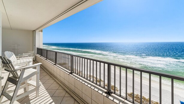 A balcony with a view of the ocean, white chairs, and a tiled floor. - 30-Foot Oceanfront Balcony |Oceanfront Pool|Heart of Destin (Destin)