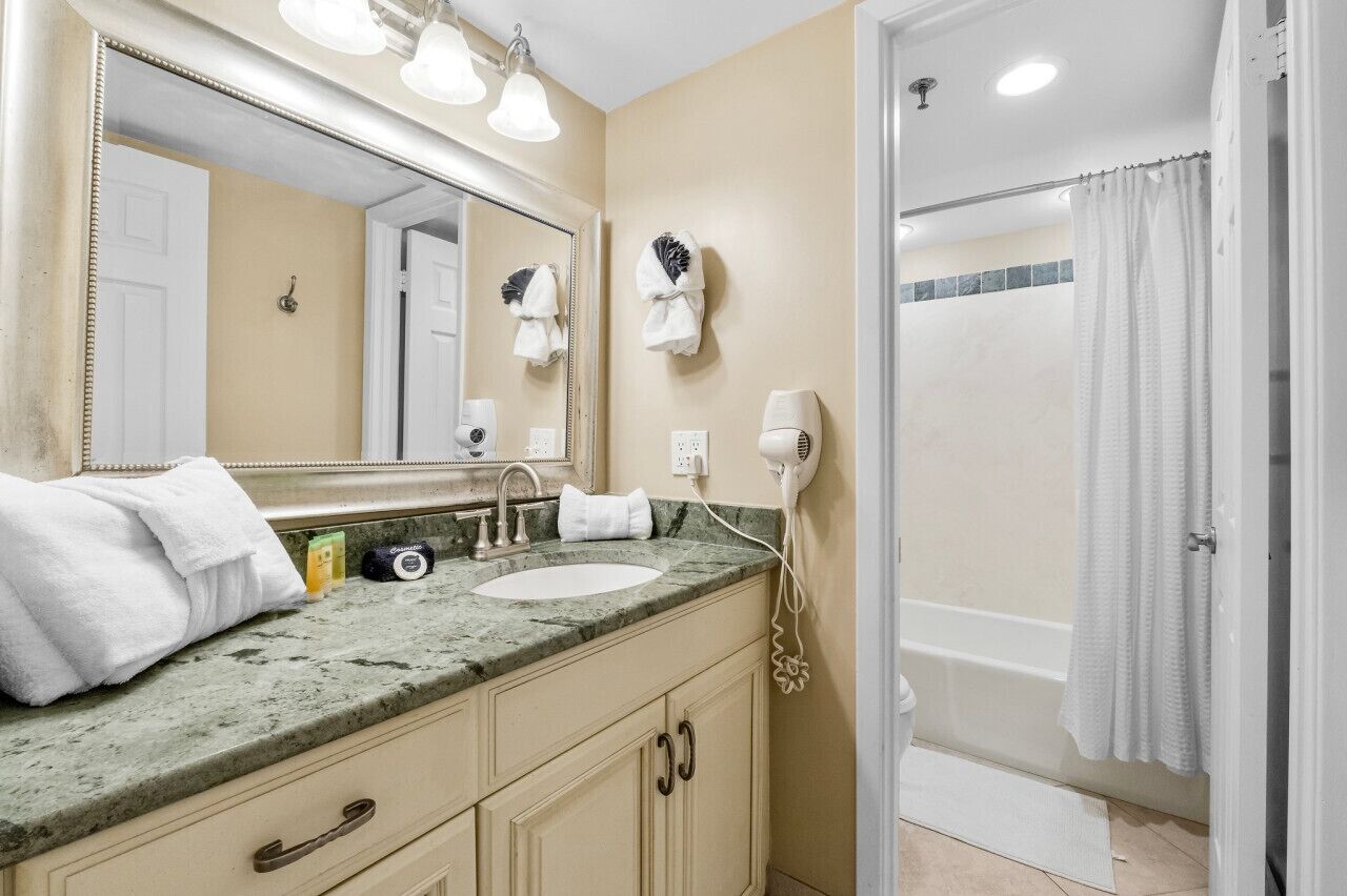 Un baño con lavabo, espejo, toallero y ducha.