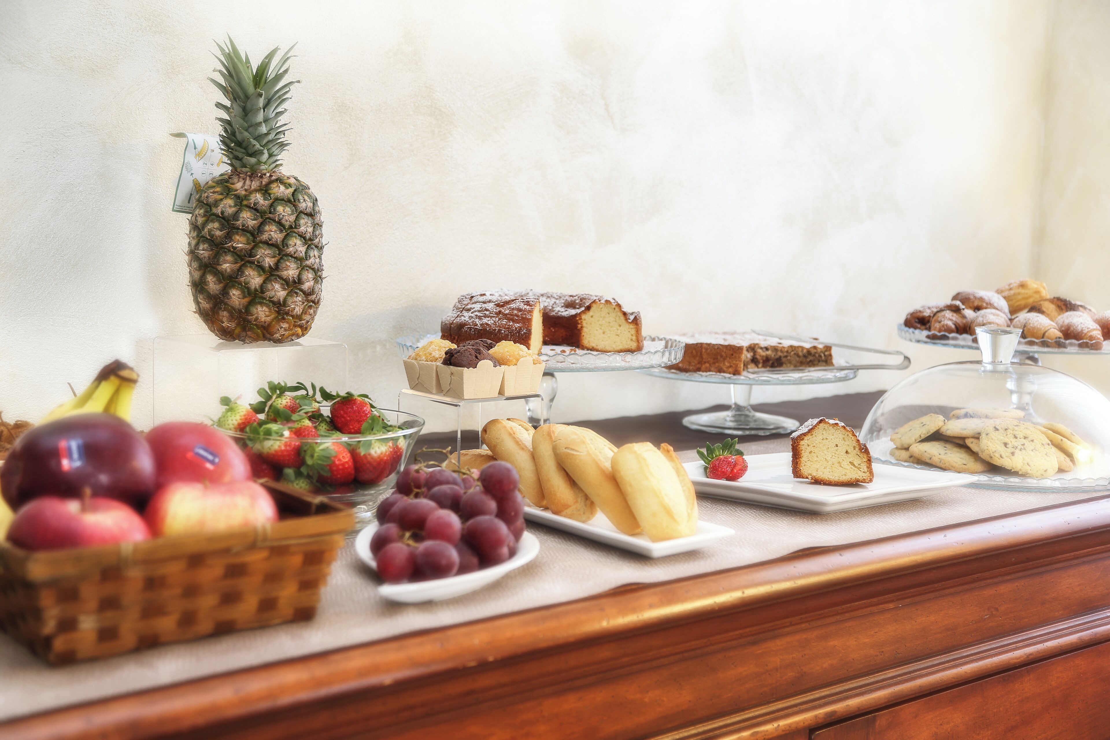 Un buffet proposant une variété de fruits, de pâtisseries et un ananas.