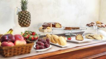 Un buffet proposant une variété de fruits, de pâtisseries et un ananas.