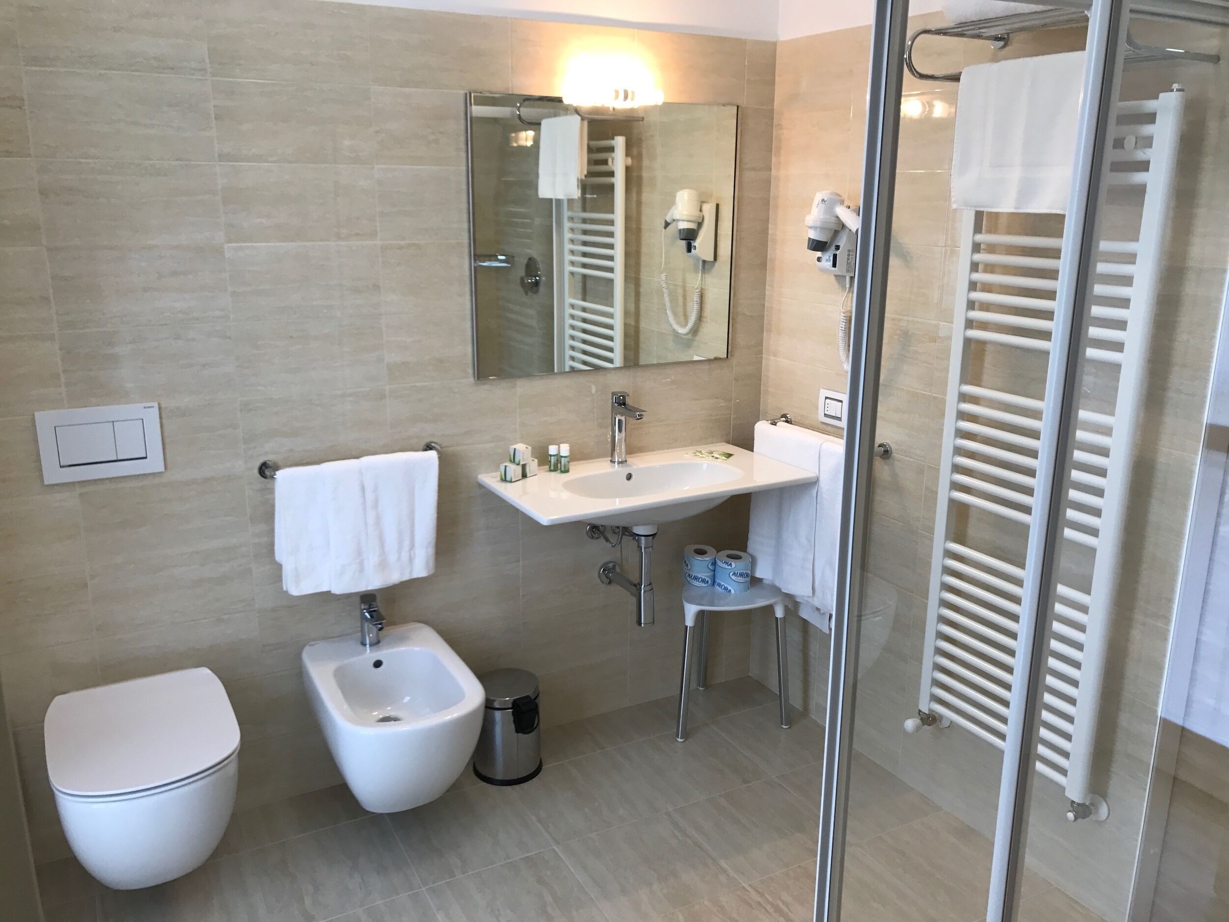 A modern bathroom with a bidet, sink, and mirror.