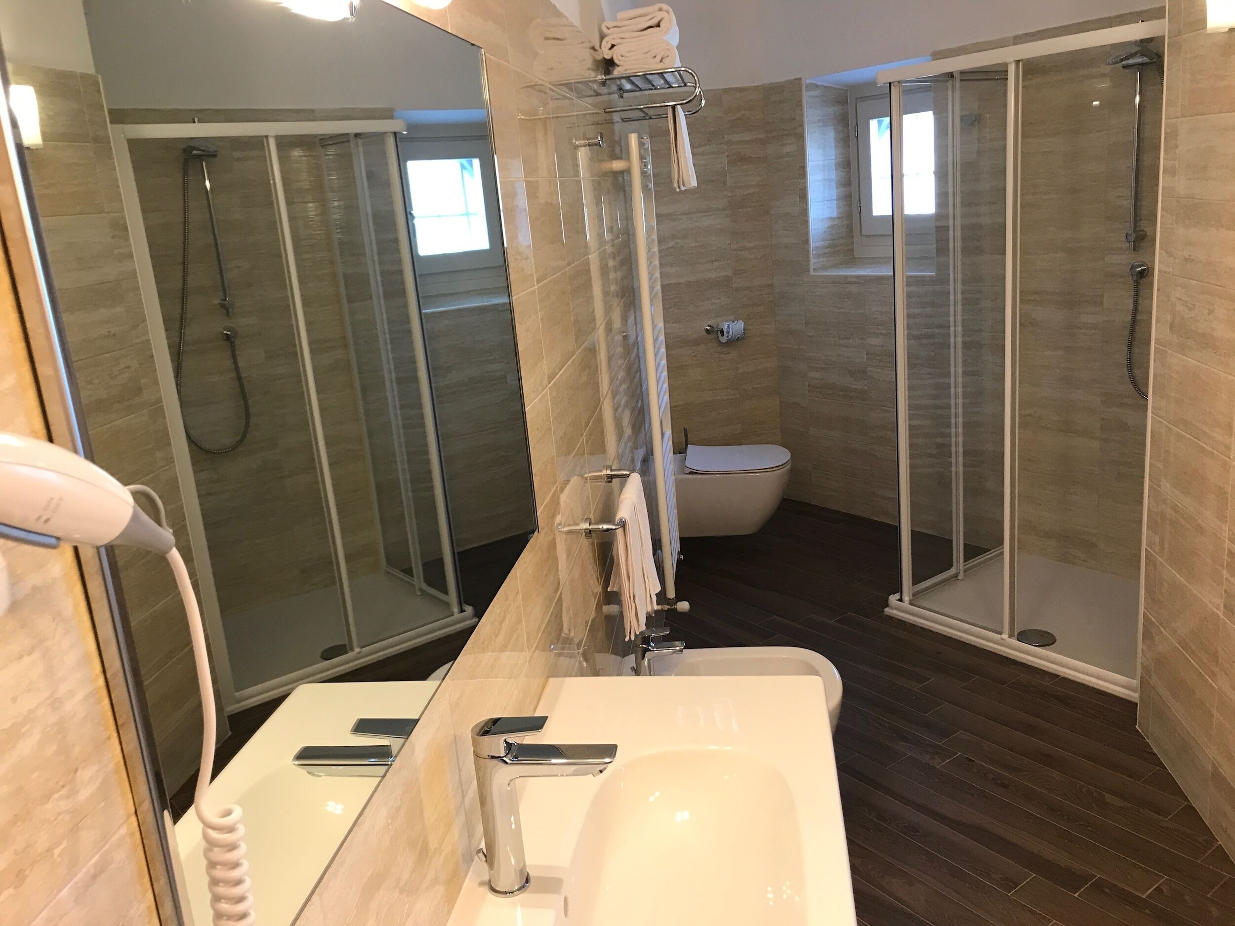 Ein modernes Badezimmer mit einer Duschkabine, einer Toilette und einem Waschbecken mit Spiegel.