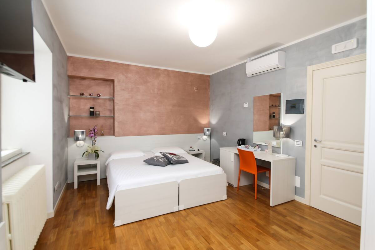 A modern bedroom with a bed, desk, chair, and built-in shelves.