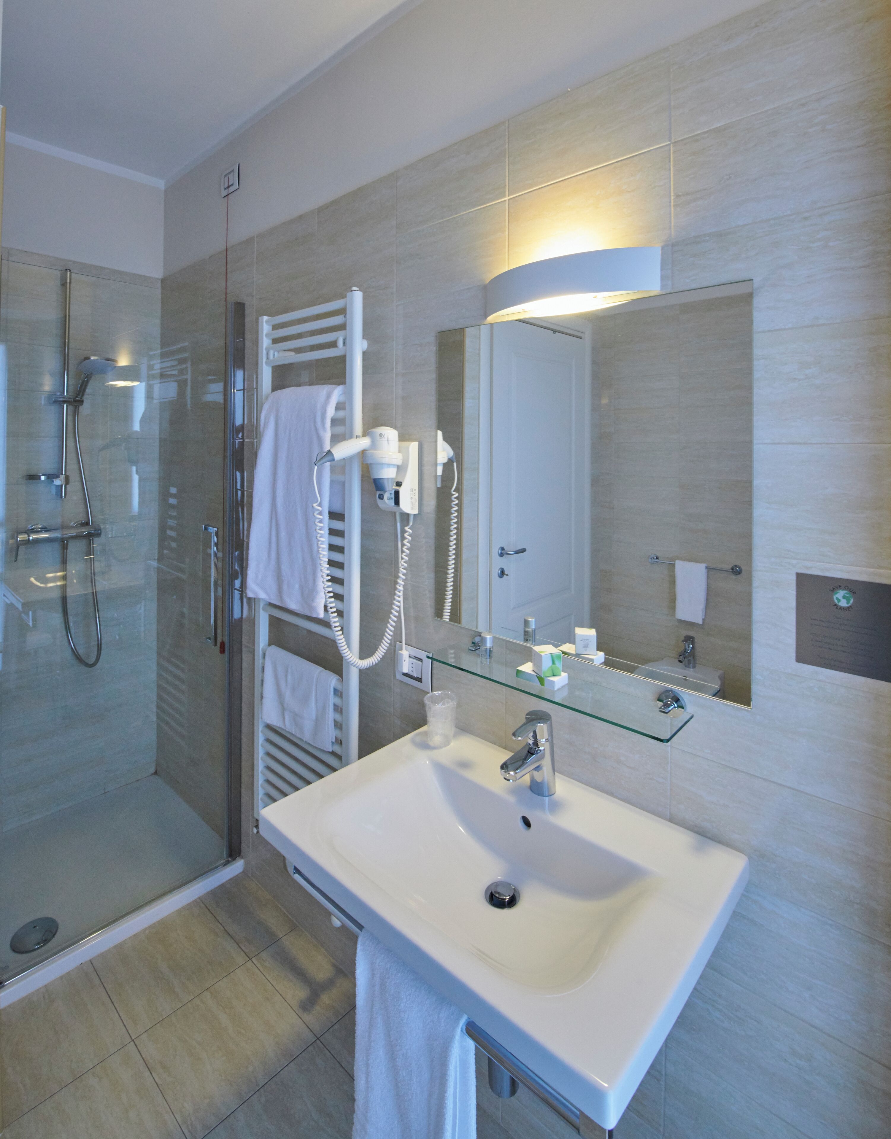 A modern bathroom with a glass shower enclosure, a white sink, and a large mirror.