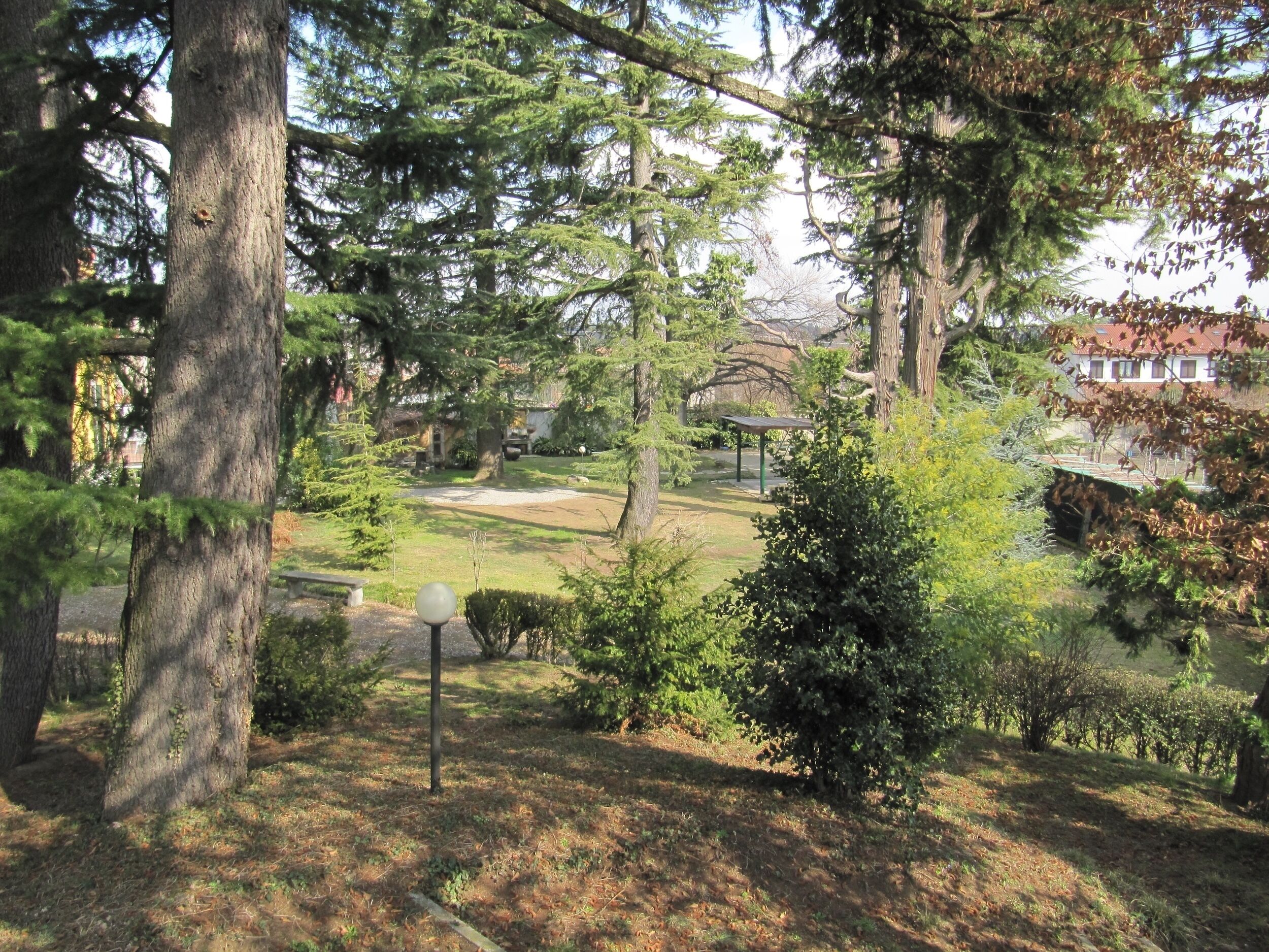 Un parc avec un kiosque, des arbres et un bâtiment en arrière-plan.