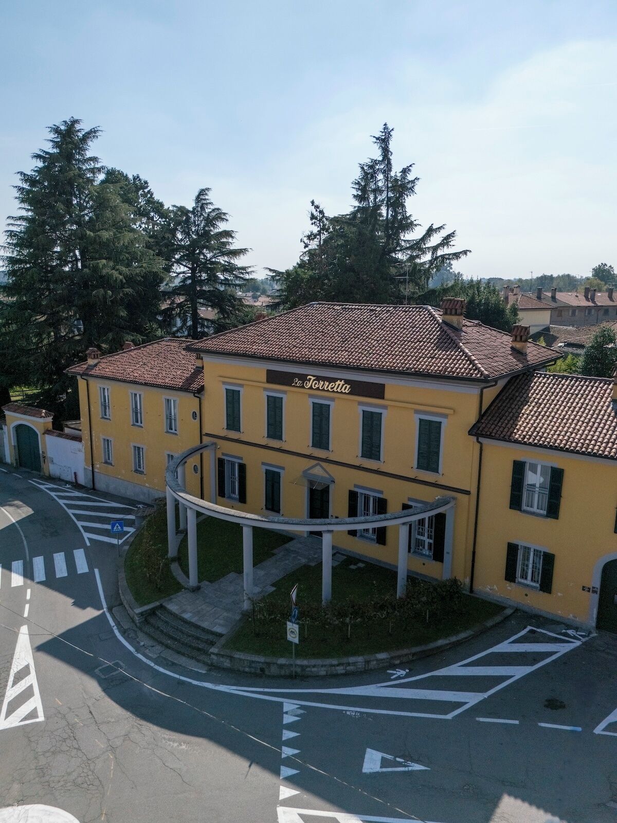 Un edificio giallo con tetto in tegole e un cartello con su scritto 'La Torretta'.