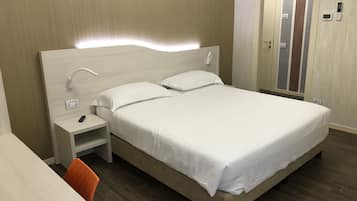 A neatly arranged hotel room with a bed, bedside table, and a chair.