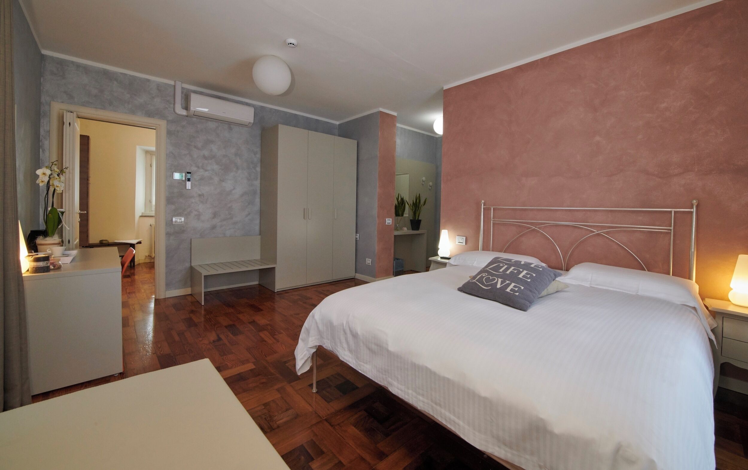 Una camera da letto con un letto, un comodino, una lampada e un condizionatore d'aria a parete.