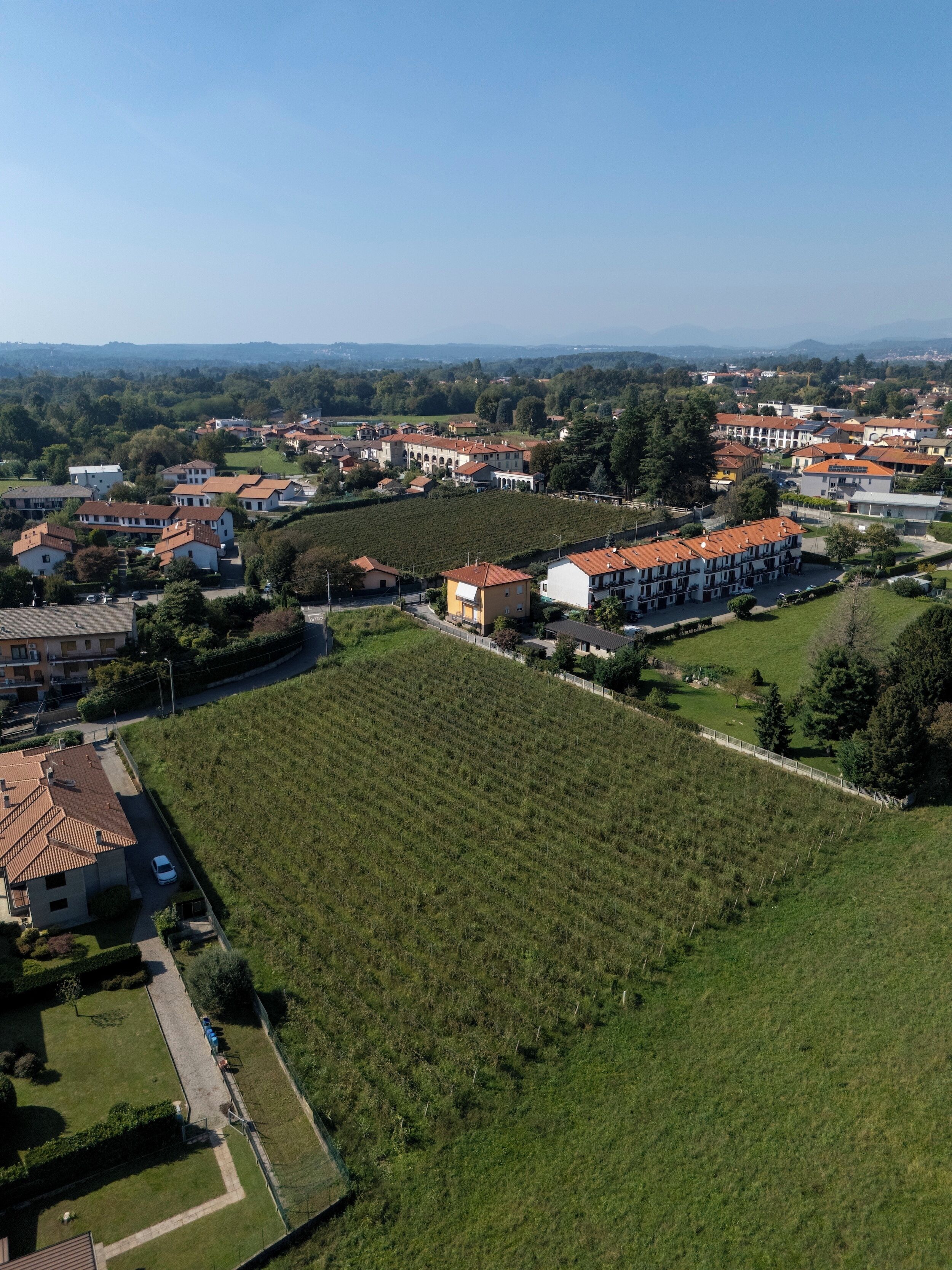 Vue aérienne d’un quartier résidentiel avec des maisons, un vignoble et un grand bâtiment doté d’un toit rouge.