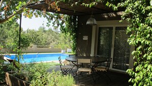 A wooden deck with a table and chairs, overlooking a swimming pool. - Charming gîte for 5 people with private heated swimming pool in St Maximin (Saint-Maximin-la-Sainte-Baume)