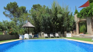 A swimming pool with clear blue water, surrounded by a low wall and a variety of trees. - Charming gîte for 5 people with private heated swimming pool in St Maximin (Saint-Maximin-la-Sainte-Baume)