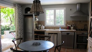 A kitchen with a round dining table, chairs, a refrigerator, a sink, and a stove. - Charming gîte for 5 people with private heated swimming pool in St Maximin (Saint-Maximin-la-Sainte-Baume)