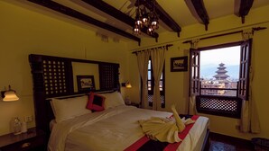Habitación de hotel con cama, mesita de noche, ventana con vista a una pagoda y techo de madera.