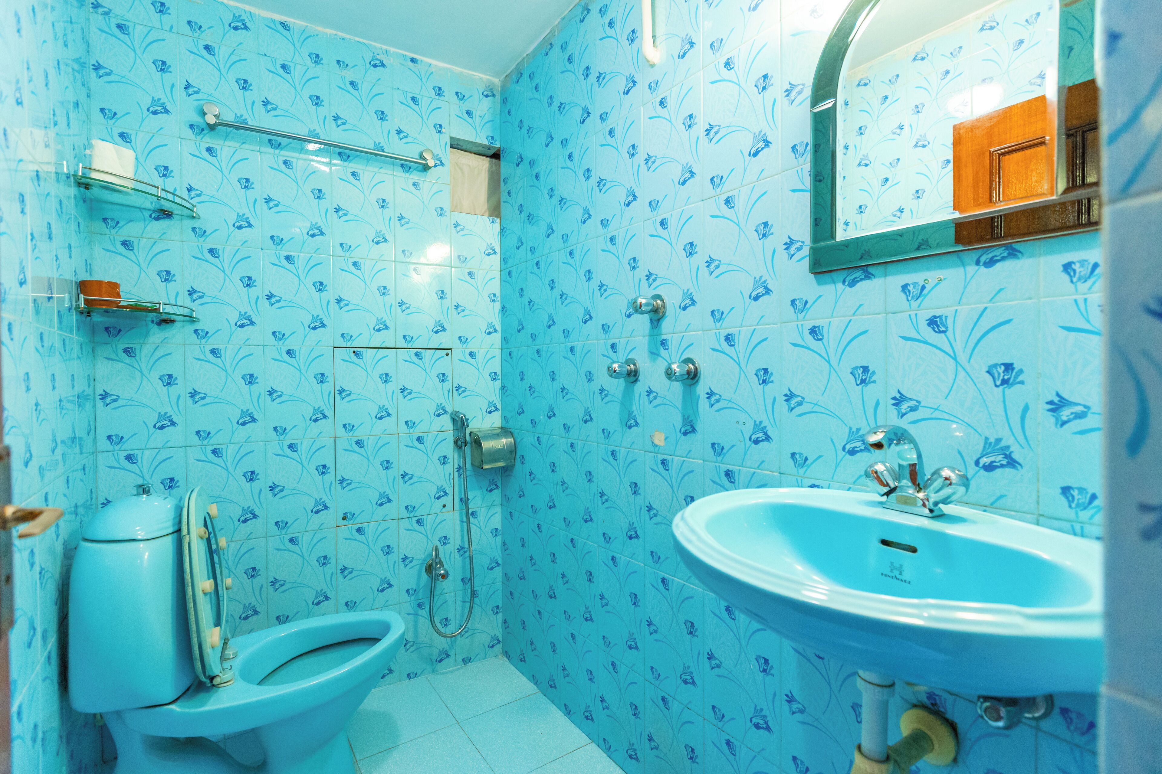 Une salle de bain comprenant des toilettes, un bidet et un lavabo, le tout orné de carreaux bleus à motifs floraux.