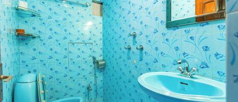 A bathroom with a toilet, bidet, and sink, all with a blue floral tile pattern.